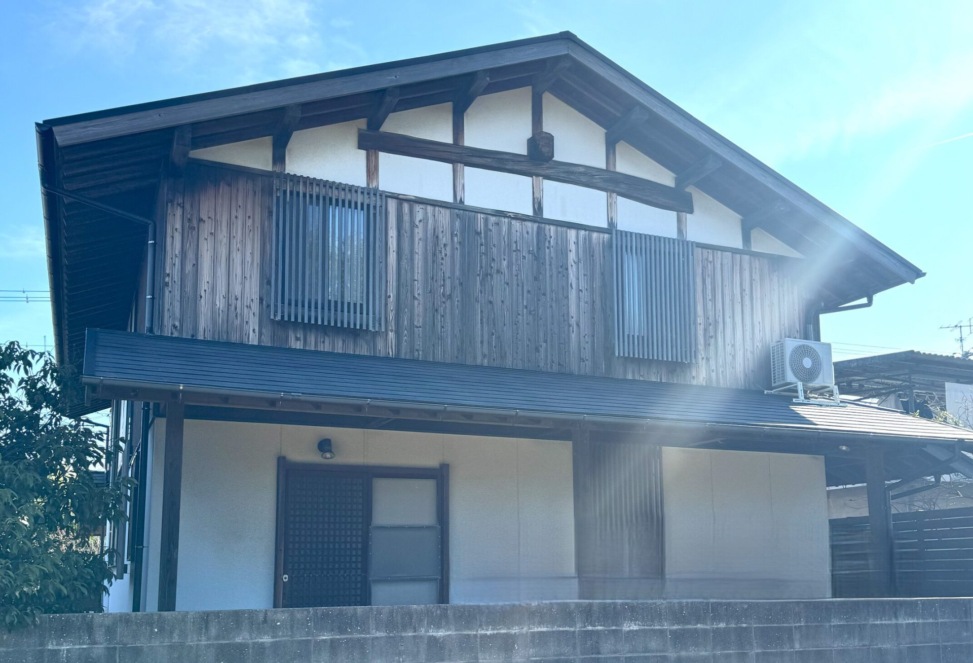 別角度から見たヘアクラックが発生したモルタル外壁と色あせた木部の塗装前外観