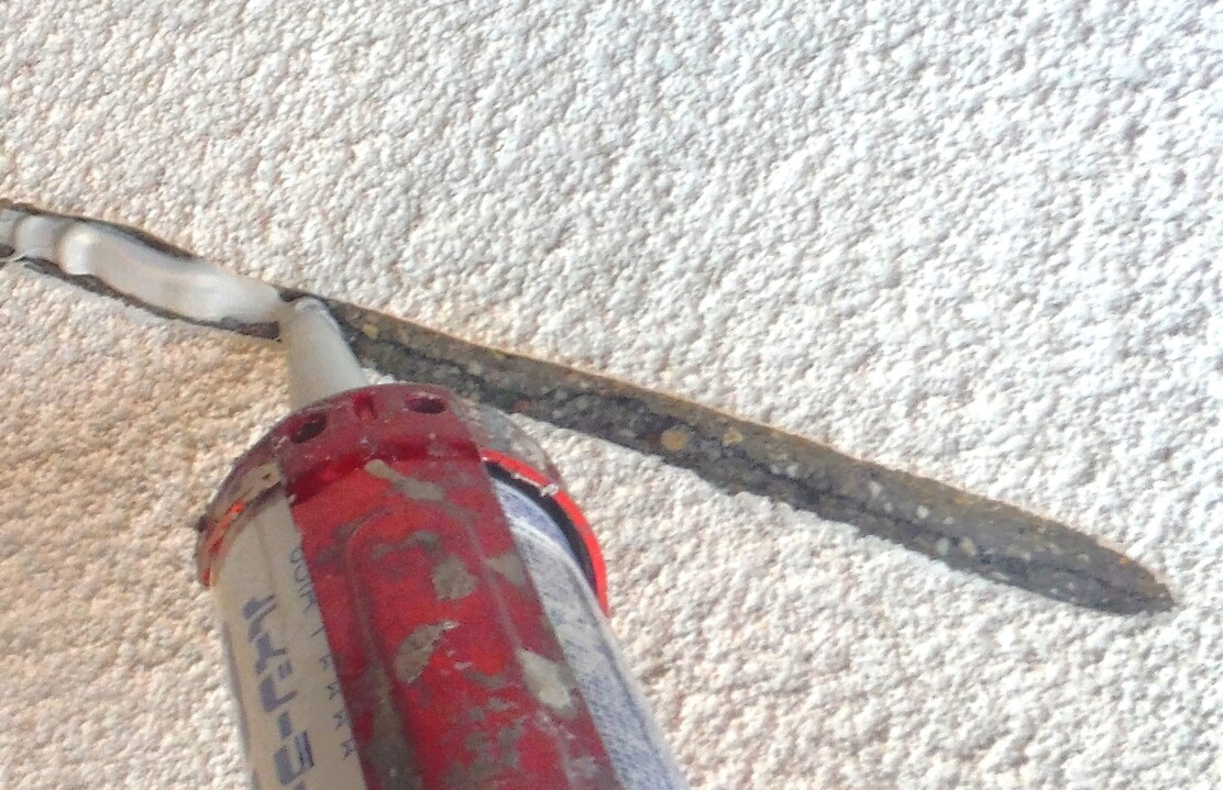 Uカット工法で開口したクラックに弾性フィラーを充填している外壁補修作業中